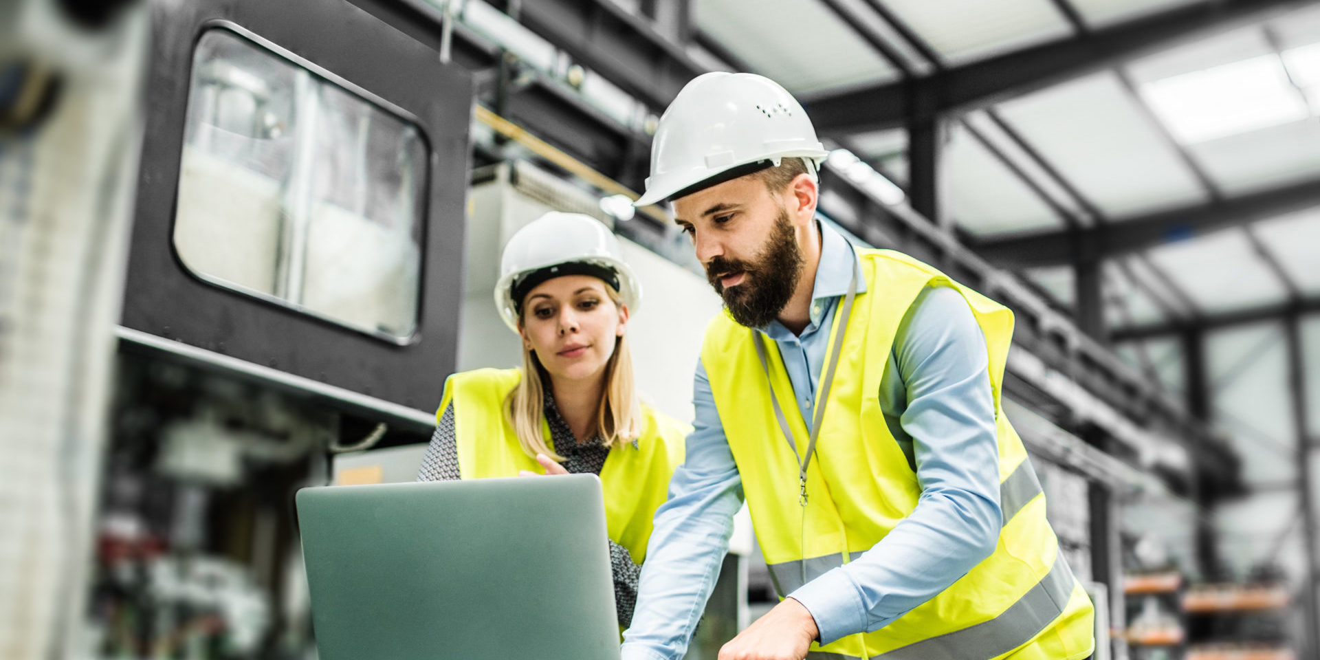 A portrait of an industrial man and woman engineer with laptop in a factory, working.