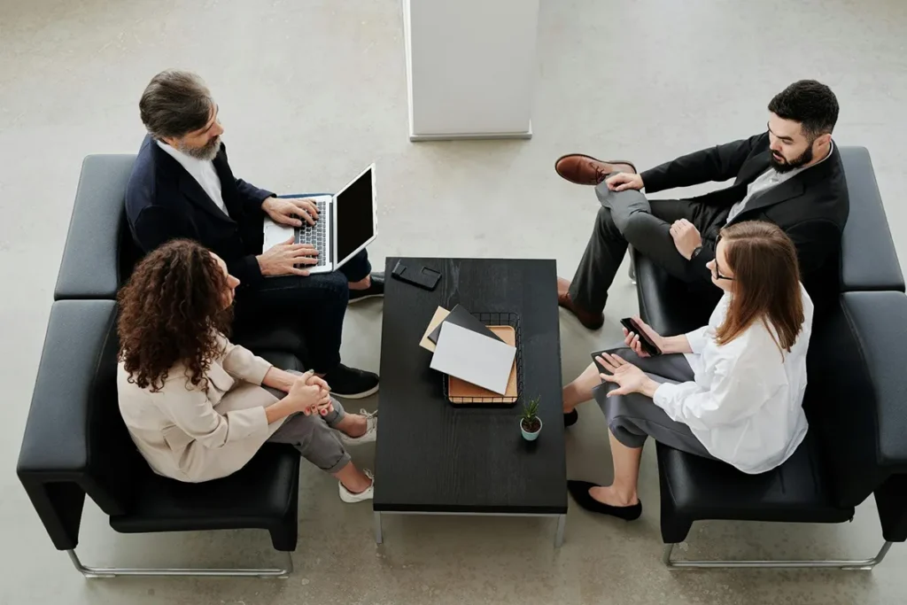 four business people sitting on couches in front of a coffee table talking