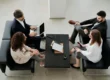 four business people sitting on couches in front of a coffee table talking