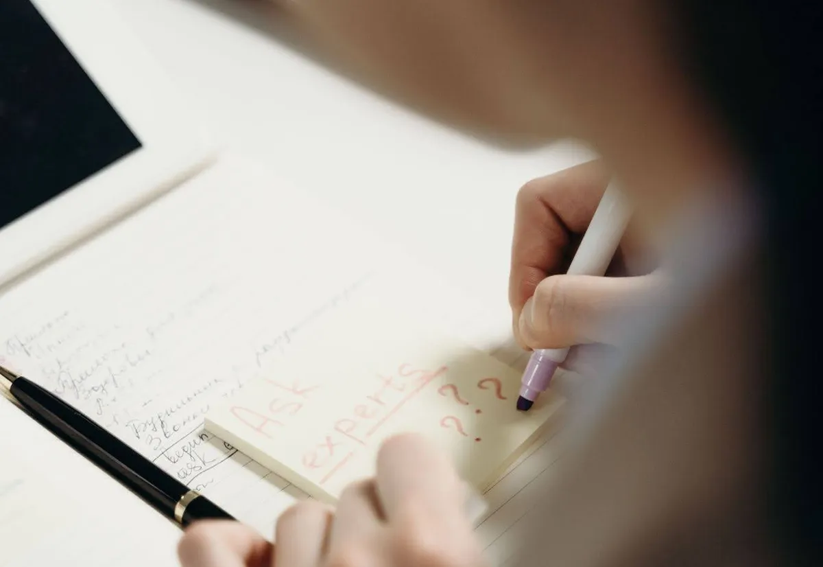 woman writing on a yellow sticky note “ask experts” woman writing on a yellow sticky note “ask experts”