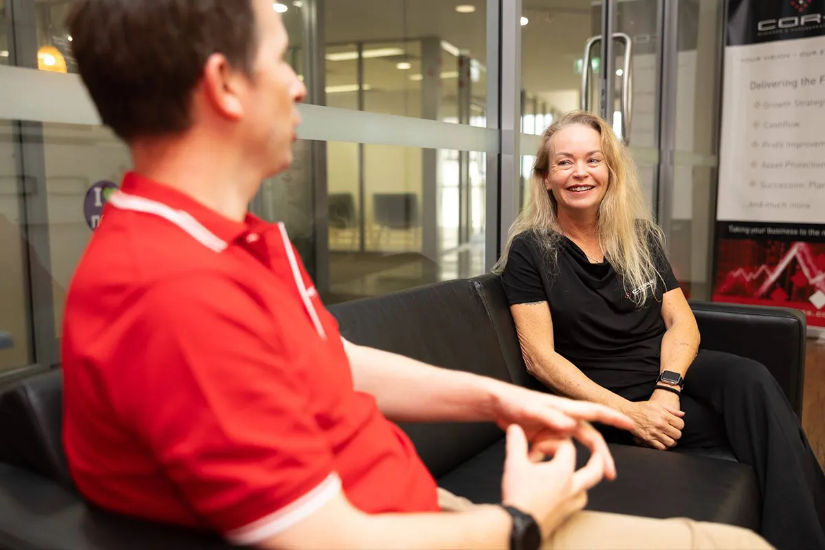 Lady sitting and smiling talking to a man in an office setting