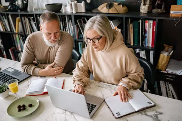 Senior couple collaborating on laptops in a cozy home office setting Senior couple collaborating on laptops in a cozy home office setting